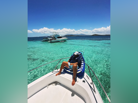 A man relaxes on the bow of a boat, enjoying the stunning turquoise waters under a clear blue sky — a perfect scene for a day of leisure on the water.