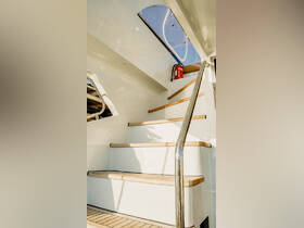 A well-lit view of the interior stairs leading up on a boat, showcasing the sleek design and safety features, perfect for exploring the vessel's amenities.