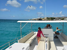 A group of guests enjoys a relaxing day on a boat, soaking in the sun and ocean views, with a scenic backdrop of the coastline.