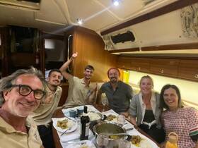 A cheerful group enjoys a meal together in the cozy dining area of a boat, celebrating their time on the water with good food and company.
