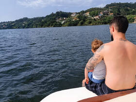 A father enjoys a peaceful moment with his child on a boat, overlooking serene waters and lush landscapes — a perfect family outing on the water.