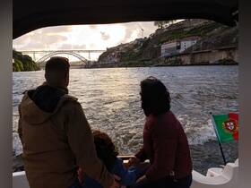A family enjoys a scenic boat ride along the river at sunset, with stunning views of the landscape and iconic bridge in the background.