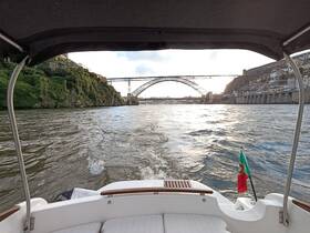 A scenic view from a boat navigating the river in Portugal, showcasing the iconic bridge and lush greenery along the banks — perfect for sightseeing and exploring the beautiful landscape.