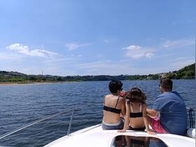 A family enjoys a sunny day on the boat, taking in the scenic views of the water and shoreline — perfect for summer outings and quality time together.