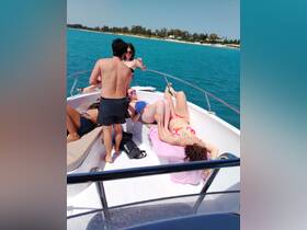A lively group enjoys a sunny day on a boat, relaxing and socializing in the turquoise waters — perfect for summer parties and fun on the water.
