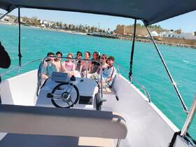 A cheerful group of friends enjoys a day out on the water, capturing memories aboard a boat with stunning turquoise waters in the background.