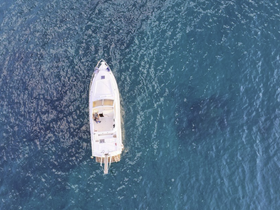Aerial view of a sleek yacht cruising through clear blue waters, showcasing the vessel's elegant design and serene surroundings.
