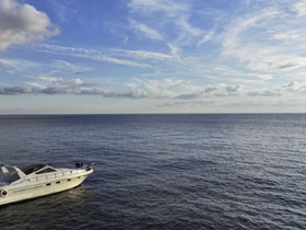 A stunning aerial view of a sleek yacht cruising on calm waters under a beautiful sky, perfect for showcasing luxury boating experiences.