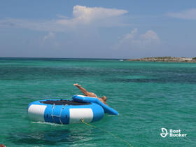 A person enjoys a fun day on a floating mat in crystal-clear waters, perfect for summer adventures and water activities.