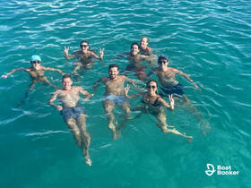 A lively group of friends enjoys a refreshing swim in crystal-clear waters, capturing the essence of fun and adventure on their boating trip.