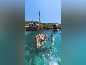 A lively group enjoys swimming near a shipwreck in crystal-clear waters, capturing the essence of adventure and exploration on their aquatic journey.