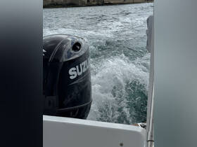Close-up of a Suzuki outboard motor with water splashing behind, showcasing the power of boating but lacking clarity in the overall scene.