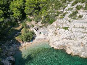 Aerial view of a serene coastline with crystal-clear waters and a rocky beach, showcasing the natural beauty of the area — perfect for exploring hidden gems on a boating adventure.