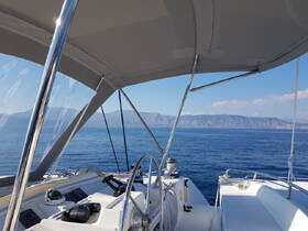 A view of the helm area inside a yacht, showcasing the console and controls with a stunning backdrop of mountains and calm waters.