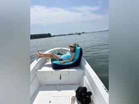 A woman relaxes on a comfortable bean bag chair aboard a boat, enjoying a sunny day on the water — perfect for leisurely outings and relaxation.