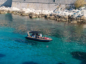 A group enjoys a scenic boat ride through crystal-clear waters, showcasing the beauty of the coastline and the joy of exploration.