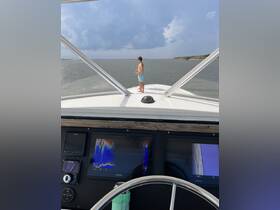 A young boy stands at the bow of a boat, gazing out at the ocean, capturing the essence of a fun day on the water.
