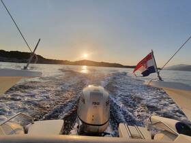 A stunning view from the back of a boat as it cruises through calm waters at sunset, showcasing the beautiful landscape and the Croatian flag waving in the breeze.