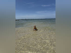 A child enjoys a sunny day playing in shallow waters, making it a perfect beach outing for families.