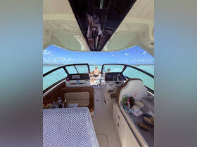 A cozy interior view of a boat showcasing the helm and seating area, with guests enjoying the sun and water in the background — perfect for relaxing on a day out at sea.