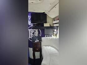 Interior view of a boat cabin featuring a cozy seating area, entertainment system, and decorative elements, perfect for relaxing on the water.