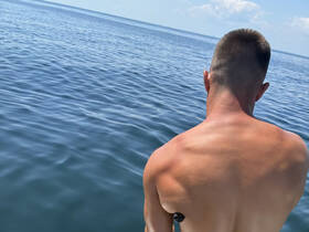 A close-up view of a person from behind, overlooking calm waters. The image lacks clarity and detail, making it difficult to discern the full context.