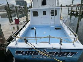 The rear view of the 'Sure Shot' boat docked at Orange Beach, showcasing its spacious deck and clean lines, perfect for fishing trips or group outings.