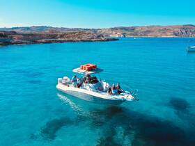 A lively group enjoys a day on a boat in crystal-clear turquoise waters, perfect for swimming and relaxation under the sun.