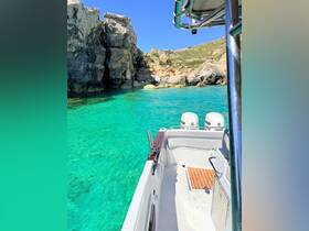 A stunning view of a boat anchored in crystal-clear turquoise waters, surrounded by rocky cliffs — perfect for exploring hidden coves and enjoying a day on the water.