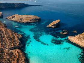 A stunning aerial view of a serene coastline with crystal-clear waters and rocky formations, perfect for exploring hidden coves and enjoying nature's beauty.