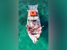 A lively group of friends enjoys a fun day on the water, celebrating together on a boat surrounded by crystal-clear turquoise waters.