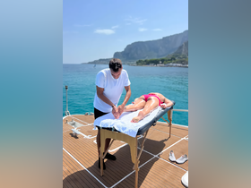 A relaxing massage session takes place on the deck of a boat, offering a serene experience against a stunning ocean backdrop — perfect for wellness retreats at sea.