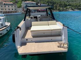 A spacious lounge area on the back of a boat, featuring comfortable seating and a serene view of the turquoise waters, perfect for relaxation and socializing.
