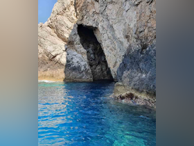 A stunning view of a rocky cave along the coastline, showcasing the vibrant blue waters — an ideal spot for exploration and adventure on the water.