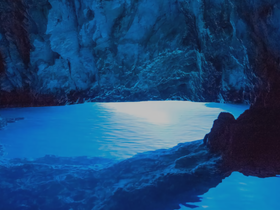 A stunning view of a blue-lit cave reflecting on calm waters, showcasing the natural beauty of coastal landscapes — perfect for eco tours and scenic boat trips.