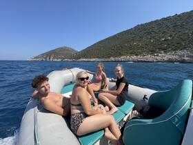 A group of friends enjoys a sunny day on a boat, surrounded by stunning coastal scenery — perfect for summer adventures and water activities.