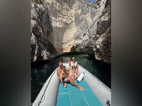 A family enjoys a scenic boat ride through a stunning cave, surrounded by towering cliffs and crystal-clear waters — a perfect adventure for exploring nature.