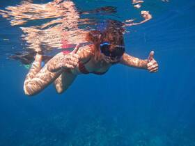 A snorkeler gives a thumbs up while exploring vibrant underwater scenery, showcasing the excitement of marine adventures.