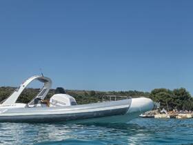 A sleek speedboat glides through clear waters, showcasing its design against a backdrop of sunbathers on the shore — perfect for summer adventures.