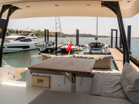 A cozy seating area inside a yacht, featuring a wooden table and plush cushions, perfect for relaxing while enjoying views of the marina.