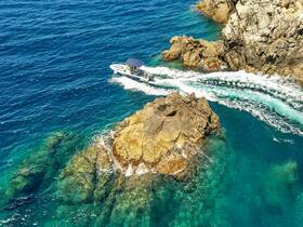 A boat navigates through crystal-clear waters near a rocky coastline, showcasing the thrill of on-water adventures.