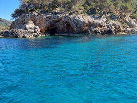 A stunning view of a rocky coastline with crystal-clear waters, perfect for exploring hidden caves and enjoying the natural beauty of the area.