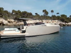 A sleek yacht glides through calm waters, showcasing its modern design against a scenic backdrop of rocky cliffs and greenery.