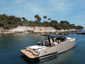 A stunning aerial view of a sleek yacht anchored near a rocky coastline, showcasing its elegant design against a picturesque backdrop.