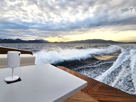 A stunning view from the deck of a boat, showcasing the wake and distant mountains as the vessel cruises through the water — perfect for those seeking adventure on the open sea.
