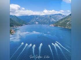 A stunning aerial view of multiple boats creating wake on the tranquil waters of Kotor, showcasing the breathtaking coastline and mountainous backdrop — perfect for adventure seekers and nature lovers.