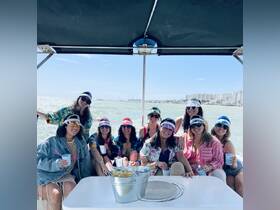 A lively group of friends enjoys a fun day on the boat, celebrating with drinks and vibrant attire — perfect for a memorable outing on the water.