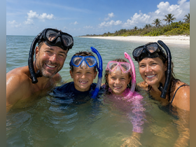 A joyful family enjoys snorkeling in shallow waters, creating unforgettable memories at the beach — perfect for family adventures and aquatic fun.