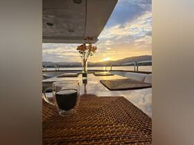 A cozy dining area on a boat, featuring a beautifully set table with a cup of coffee and flowers, perfect for enjoying sunsets while cruising.