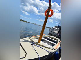 A close-up view of a small boat docked by the water, showcasing its structure and surroundings under a bright blue sky.